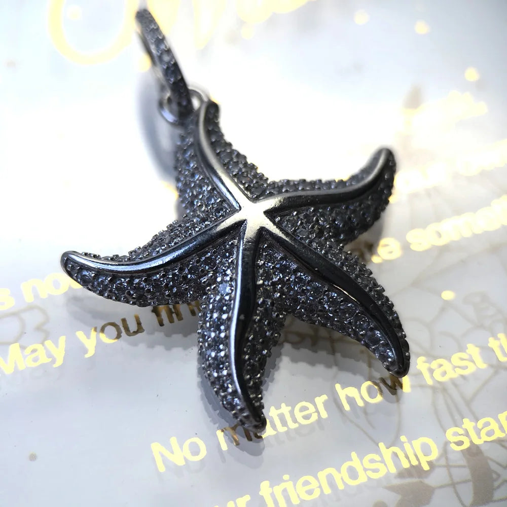 Silver-tone starfish pendant with dense pavé clear stones shown at an angle under bright light.