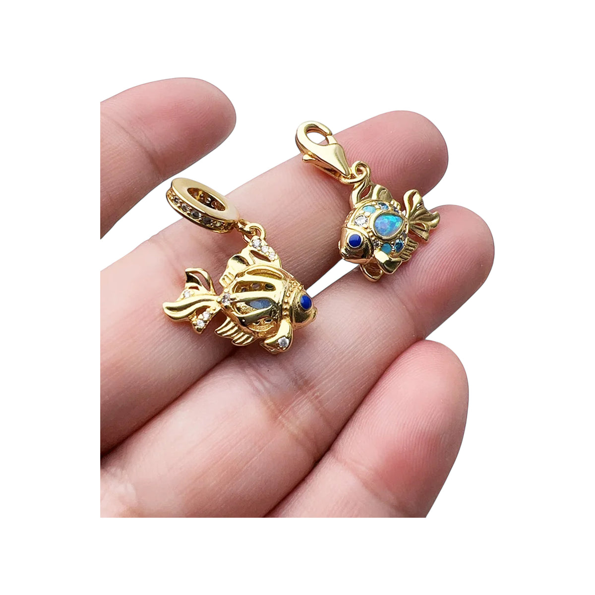 Two gold-tone fish dangle charms held between fingers to show size and detail