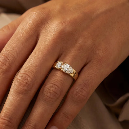 hand wearing a gold-tone bypass ring with pear and round-cut stones on the finger