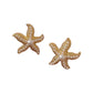 Pair of gold-tone starfish stud earrings shown on a brown surface