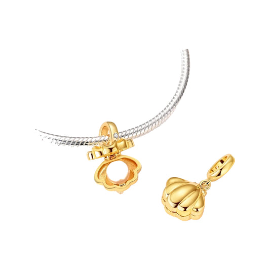 Gold-tone clamshell dangle charm with pearl on a silver-tone snake bracelet and closed shell beside it