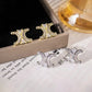 Two-tone double crescent baguette studs arranged beside a velvet-lined jewelry box and paper