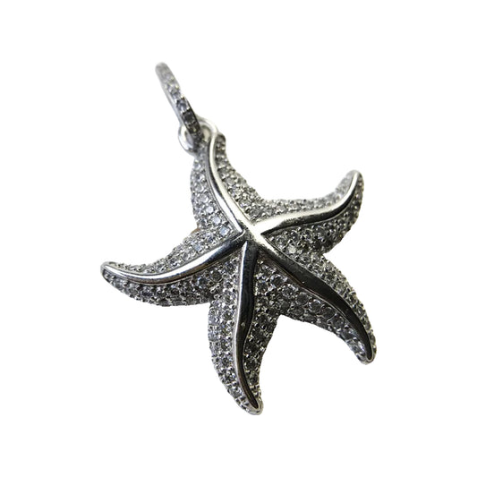 Close-up of a silver-tone pavé starfish pendant with polished raised lines and a bail for a chain.