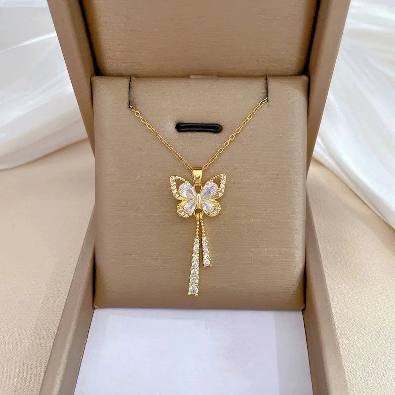 Gold-tone butterfly pendant with dangling crystal accents presented in a box insert