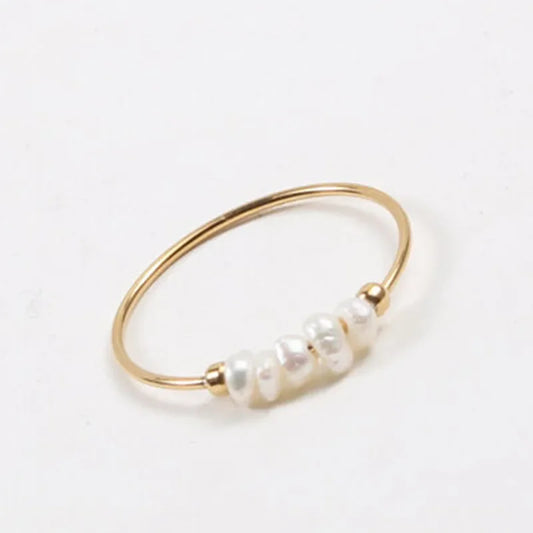 Thin gold-tone ring with five small irregular white pearly beads on the front, shown on a white background.
