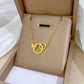 Gold-tone interlocking rings pendant with textured butterfly on a cushioned box