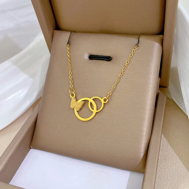 Gold-tone interlocking rings pendant with textured butterfly on a cushioned box