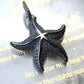 Silver-tone starfish pendant with dense pavé clear stones shown at an angle under bright light.