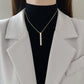 Gold-tone vertical bar pendant necklace worn at the collarbone
