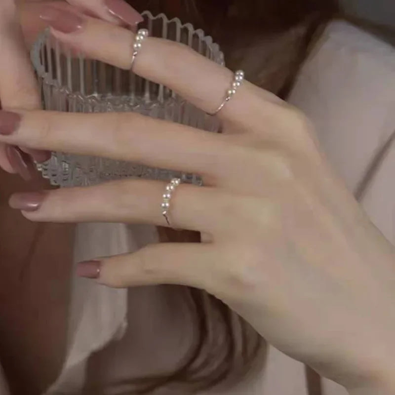 Gold-tone irregular pearl bead thin stacking rings worn on multiple fingers