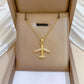 Gold-tone airplane pendant displayed in a tan padded jewelry box