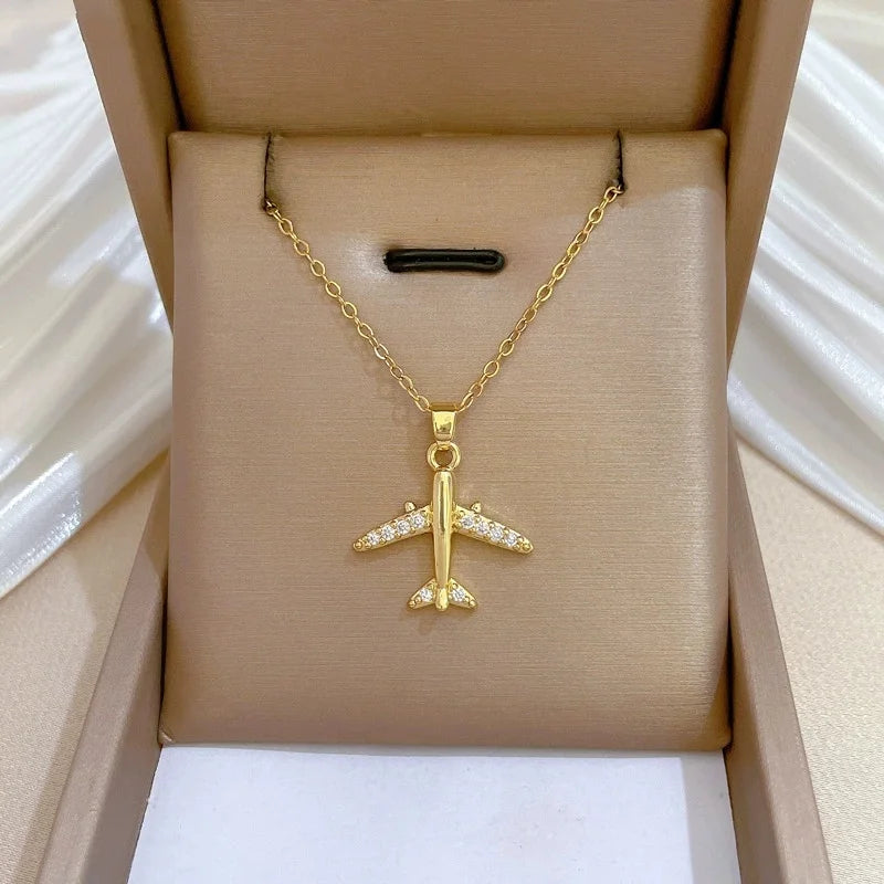 Gold-tone airplane pendant displayed in a tan padded jewelry box