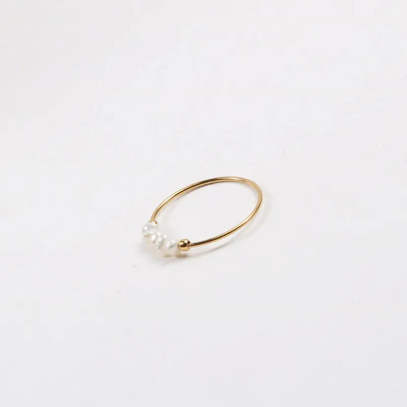Gold-tone thin ring with irregular pearl beads photographed flat on a white backdrop