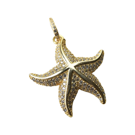 Gold-tone pavé starfish pendant laid on a zodiac illustration showing textured pavé detail