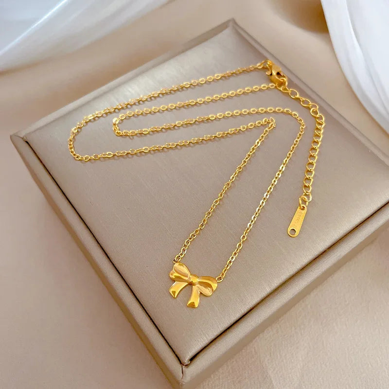 Gold-tone bow necklace with delicate chain laid on a cushioned display