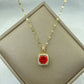 gold-tone pendant with a vibrant red cushion center stone and clear halo on a chain