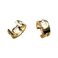 Pair of gold-tone huggie hoops with channel white stones on a textured painted backdrop