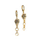 Gold-tone leopard head huggie earrings with linked rings and green eye accents on a white prop