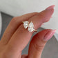 gold-tone bypass ring with two pear-cut stones held between fingertips