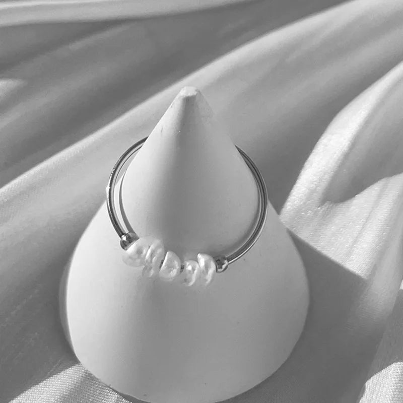 Gold-tone stacking ring with irregular pearls displayed on a cone stand