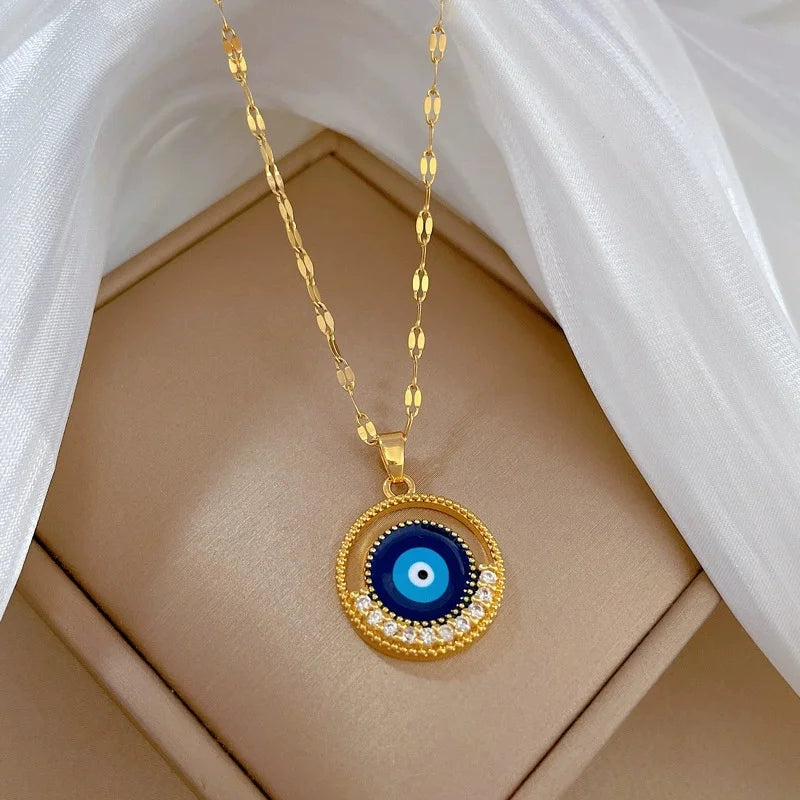 Evil-eye gold-tone pendant with sunray fringe arranged on a soft beige display pad