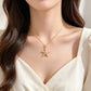 Gold-tone starfish pendant necklace worn at the collarbone with a white v-neck top