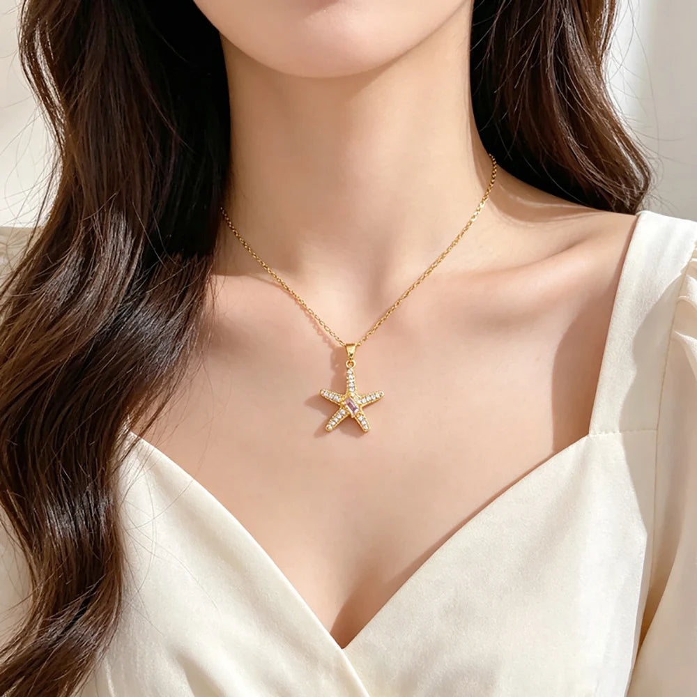 Gold-tone starfish pendant necklace worn at the collarbone with a white v-neck top