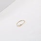 Delicate gold-tone thin ring featuring a row of irregular pearl beads on white