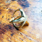 Gold-tone starfish pavé openwork ring angled on a wood surface showing side profile