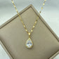 gold-tone teardrop pendant with a large clear center stone and halo on a fine chain