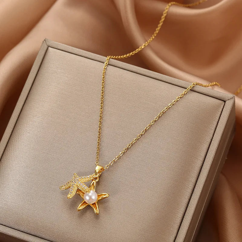 Gold-tone pave starfish pendant with a pearl-accented starfish draped on a boxed satin backdrop
