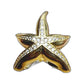 Gold-tone starfish pavé ring top view on pastel textured painted backdrop