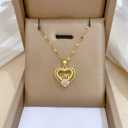 Gold-tone heart pendant with decorative openwork shown on a cushioned box display