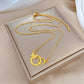 Gold-tone interlocking rings pendant necklace arranged on a gift box