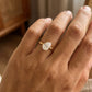 gold-tone pear-cut solitaire ring worn on the ring finger against a neutral background