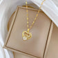 Gold-tone heart pendant on a patterned chain in a tan jewelry tray