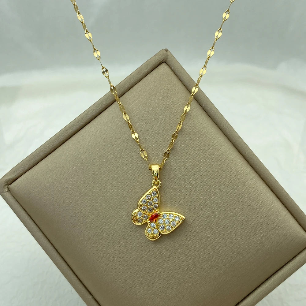 butterfly pendant necklace with clear wings and a red center displayed on a tilted beige box
