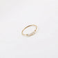 Simple gold-tone stacking ring with irregular pearl beads displayed on a white surface