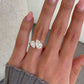 hand wearing a gold-tone bypass ring with two pear-cut stones on the ring finger
