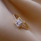 Gold-tone square halo adjustable open ring with clear center stone on champagne satin