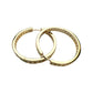 Two gold-tone hinged hoops with clear channel-set stones shown flat on a painted seascape