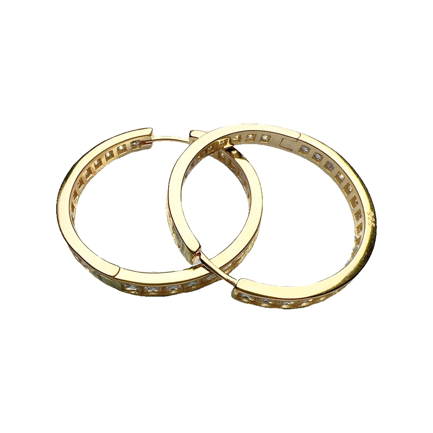 Two gold-tone hinged hoops with clear channel-set stones shown flat on a painted seascape