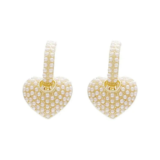 Pair of gold-tone huggie hoops with heart-shaped pendants covered in pearls