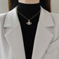 Gold-tone evil eye pendant worn at the collarbone