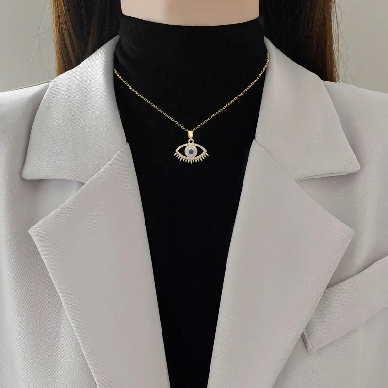 Gold-tone evil eye pendant worn at the collarbone