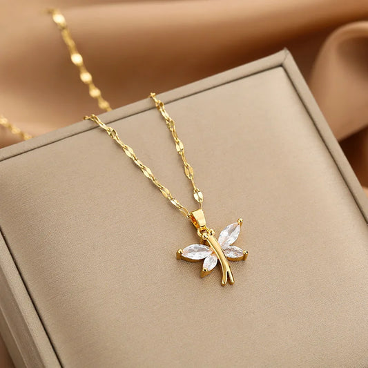 Gold-tone butterfly pendant necklace with four clear marquise stones on a textured link chain, displayed on a beige box.