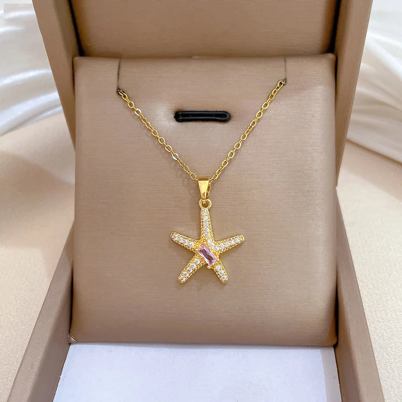 Gold-tone starfish pendant presented inside a tan jewelry box on a padded insert
