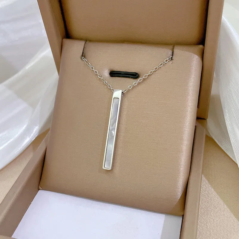65f9334c-a929-4126-b4eb-decec0653f75 silver-tone vertical bar pendant with pearlescent inlay on beige display cushion