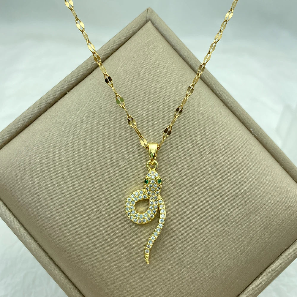 gold-tone snake pendant with pavé clear stones and green stone eyes on a fine chain