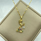 gold-tone mermaid pendant set with multicolored stones holding a dangling clear teardrop